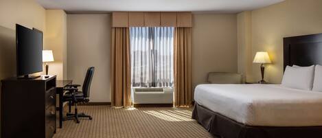 A hotel room with a bed, desk, chair, television, and a window with curtains.