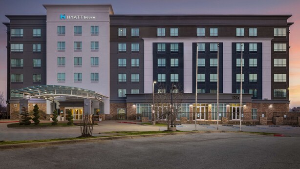 A modern hotel building with a glass entrance, multiple floors, and a prominent 'Hyatt House' sign. - Hyatt House Bentonville/Rogers (Rogers)