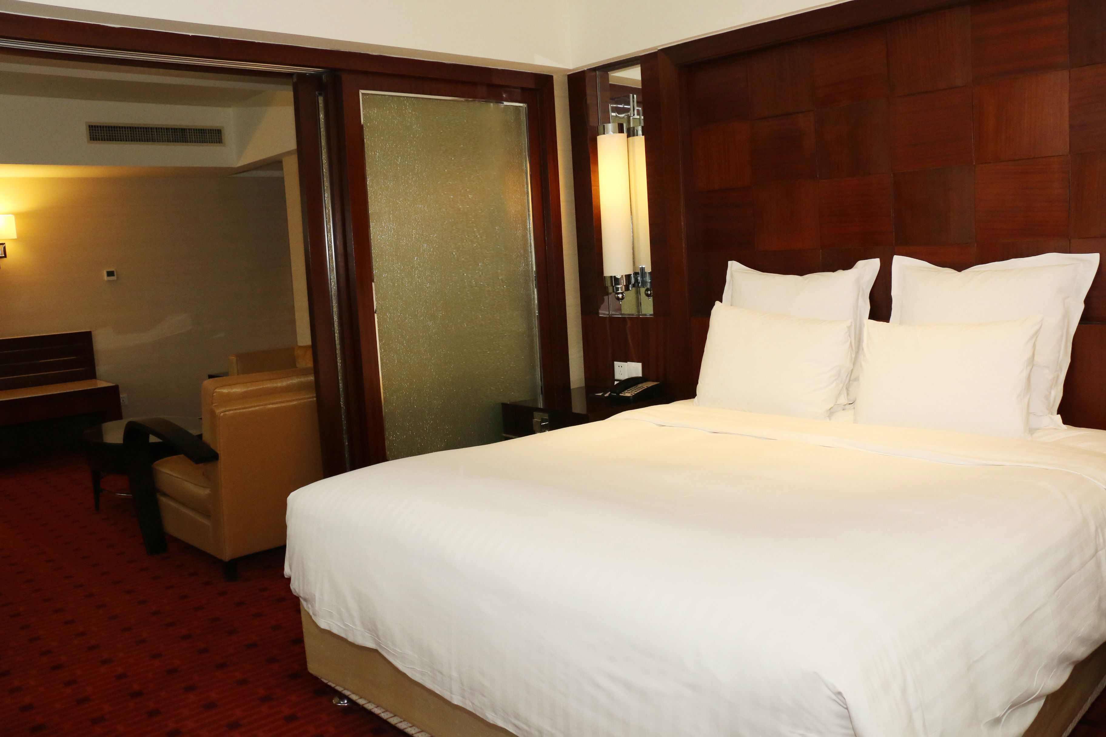 Una habitación de hotel con una cama grande, un escritorio, una silla y un espejo.