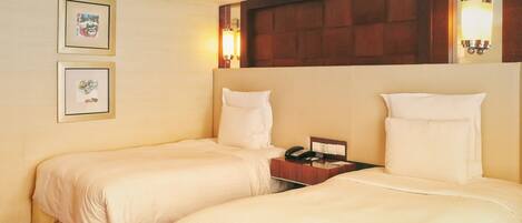 A hotel room with two beds, a nightstand, and a wall-mounted lamp.