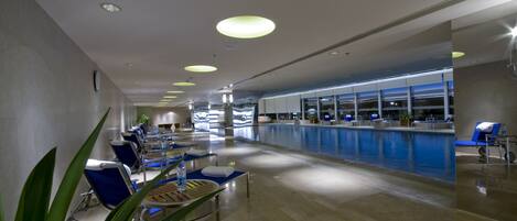 A hotel lobby with a reception desk, seating area, and a pool.