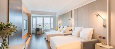 Una habitación de hotel moderna con dos camas, un escritorio y vistas a la ciudad.