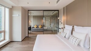 A modern bedroom with a large bed, a sofa, and a glass partition. - Beijing Pudi Hotel (Beijing)