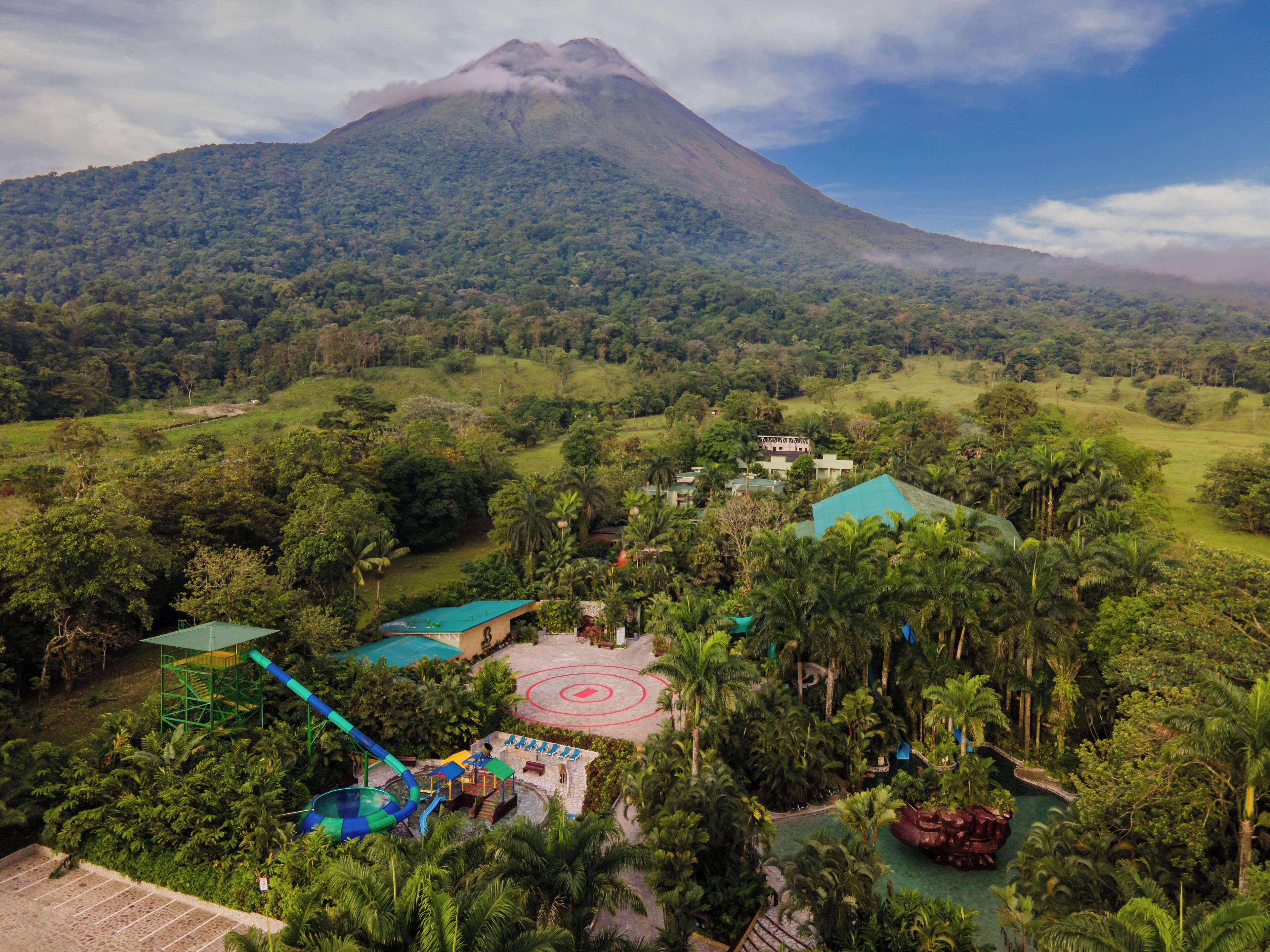 Un resort con piscina, parque infantil y vistas a la montaña.