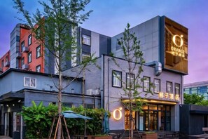Un edificio moderno con un'insegna arancione ben visibile, posti a sedere all'aperto e un'area giardino curata.