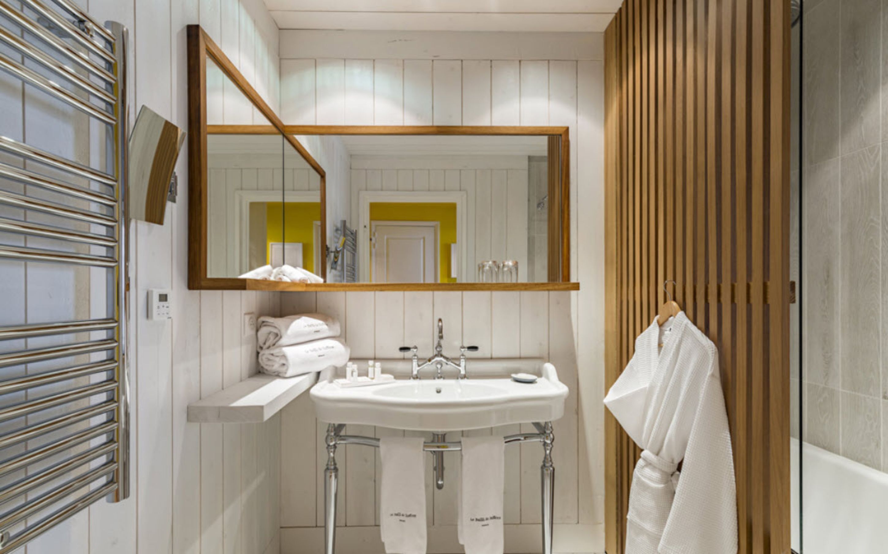 A modern bathroom with a large mirror, a sink, and two towel racks.