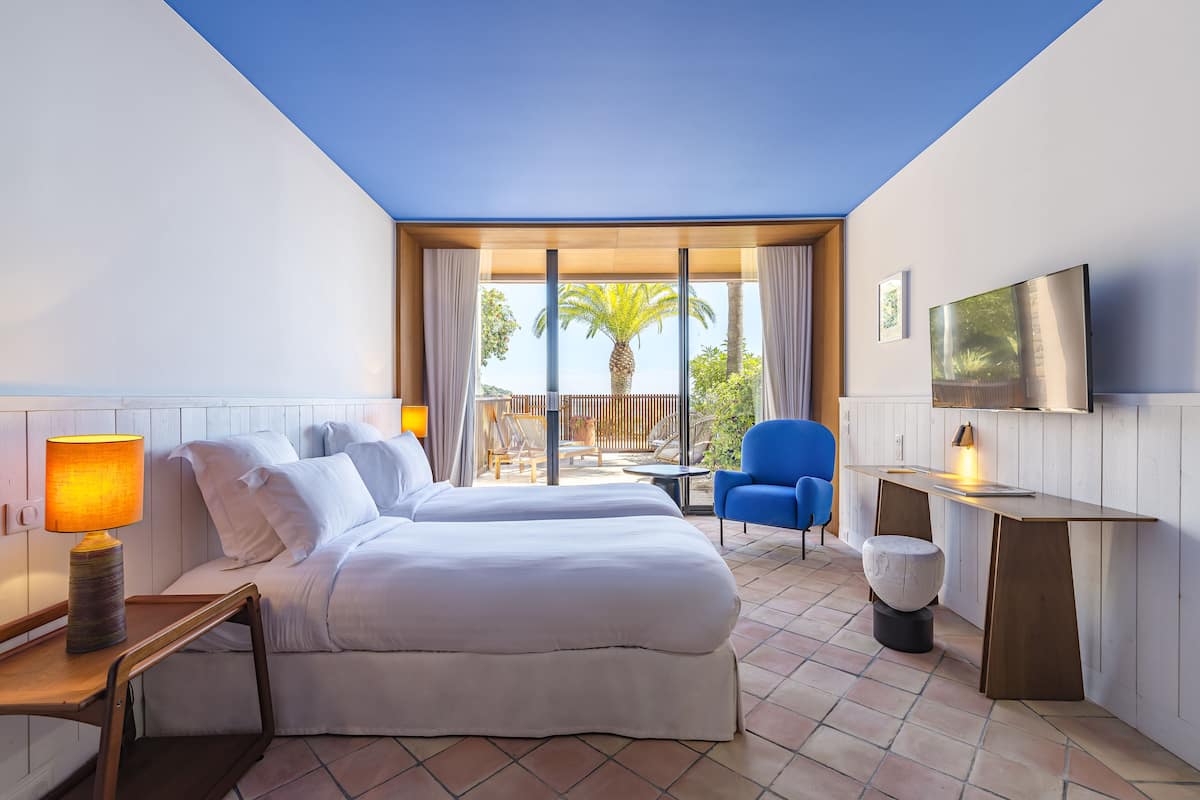 Una habitación de hotel con dos camas, un escritorio, un televisor y vistas al exterior.