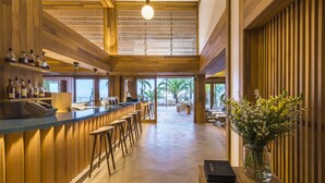 Un bar moderno con detalles de madera, taburetes y vistas al exterior.