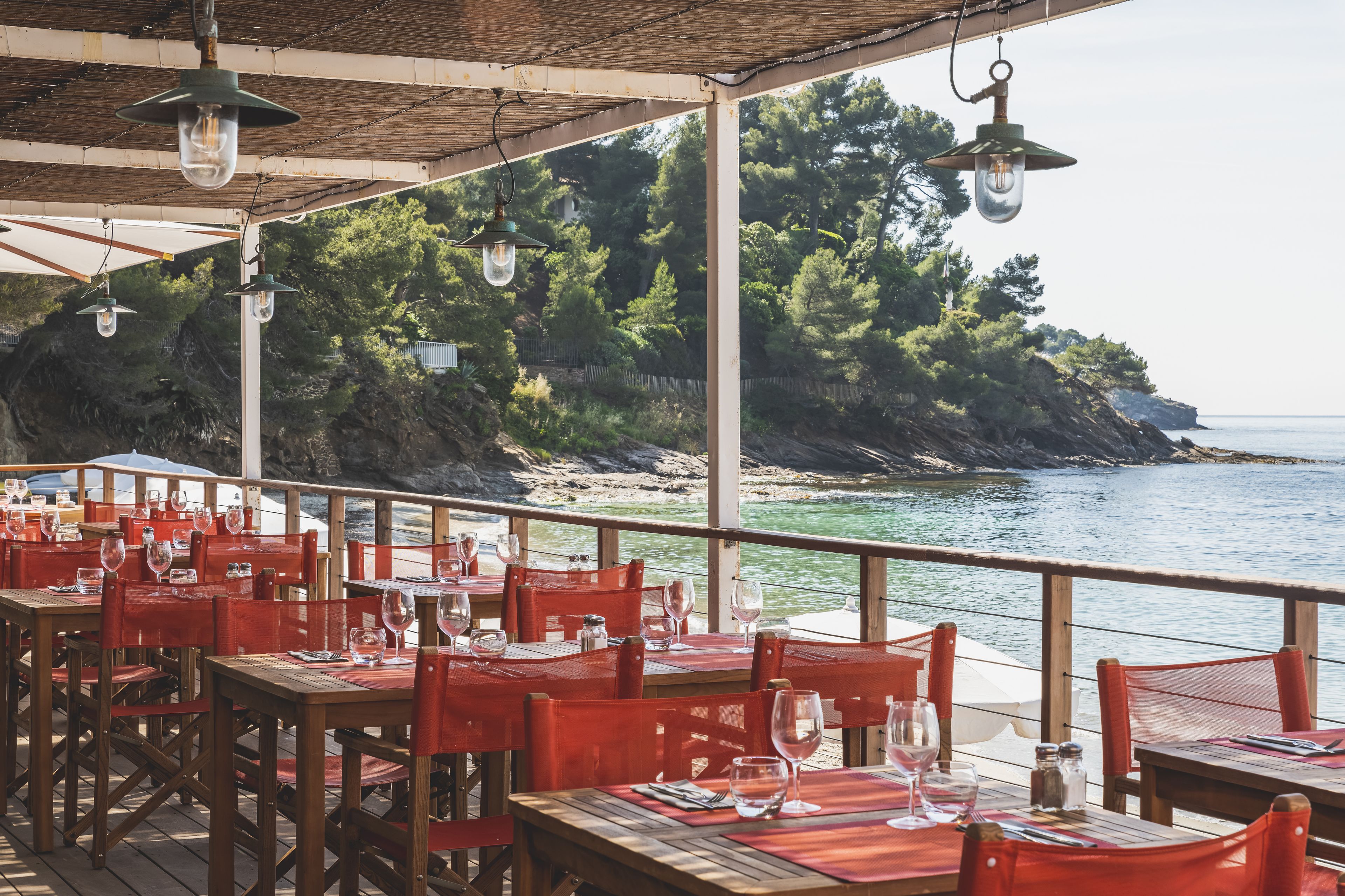 Een restaurant aan zee met tafels en stoelen, met uitzicht op de oceaan.