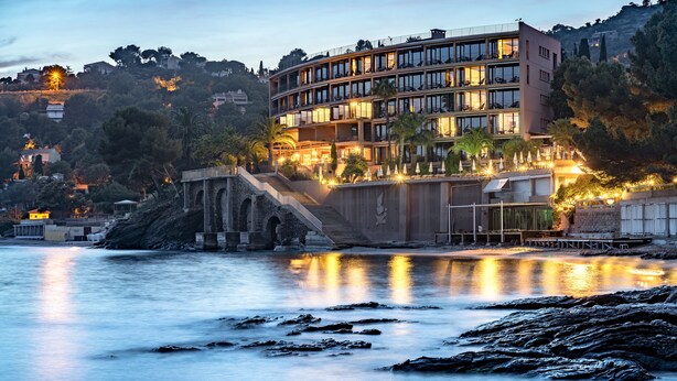 Un hotel moderno con varios pisos, una escalera destacada y vistas al mar.