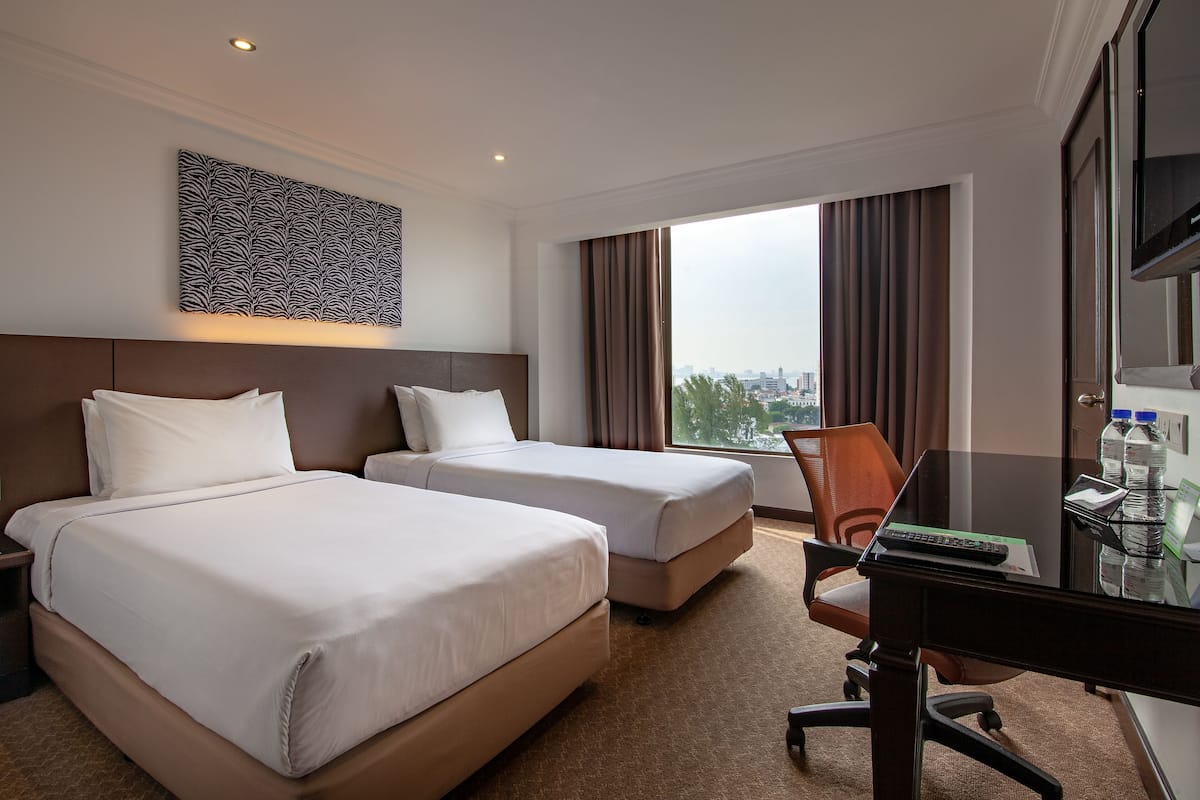 A hotel room with two beds, a desk, a chair, a TV, and a large window with curtains.