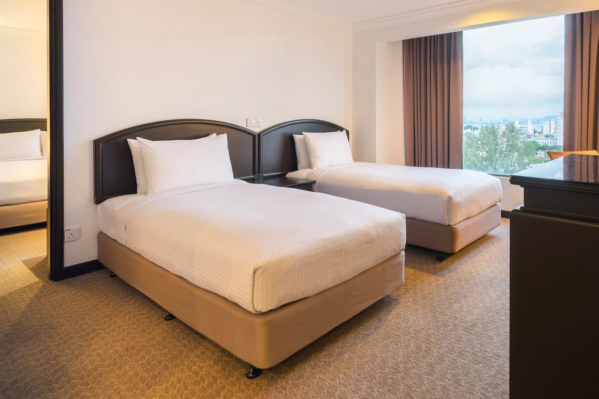 A hotel room with two beds, a desk, and a view of the city.
