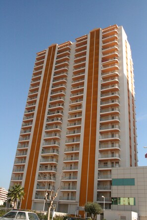 A high-rise building with multiple balconies and a modern architectural design. - Apartamentos Ambar Beach (Calpe)