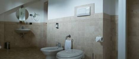 Un baño con dos inodoros, un lavamanos, un espejo y un dispensador de papel higiénico.