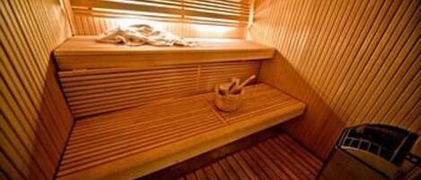 A sauna with wooden benches and a bench with a towel.