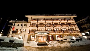 Un hotel con una entrada cubierta de nieve y balcones iluminados.