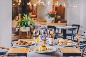 Une table à manger avec des assiettes remplies de nourriture, des verres de vin et une bouteille de champagne.
