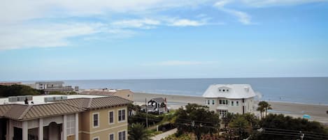 A multi-story building with balconies overlooking a beach.