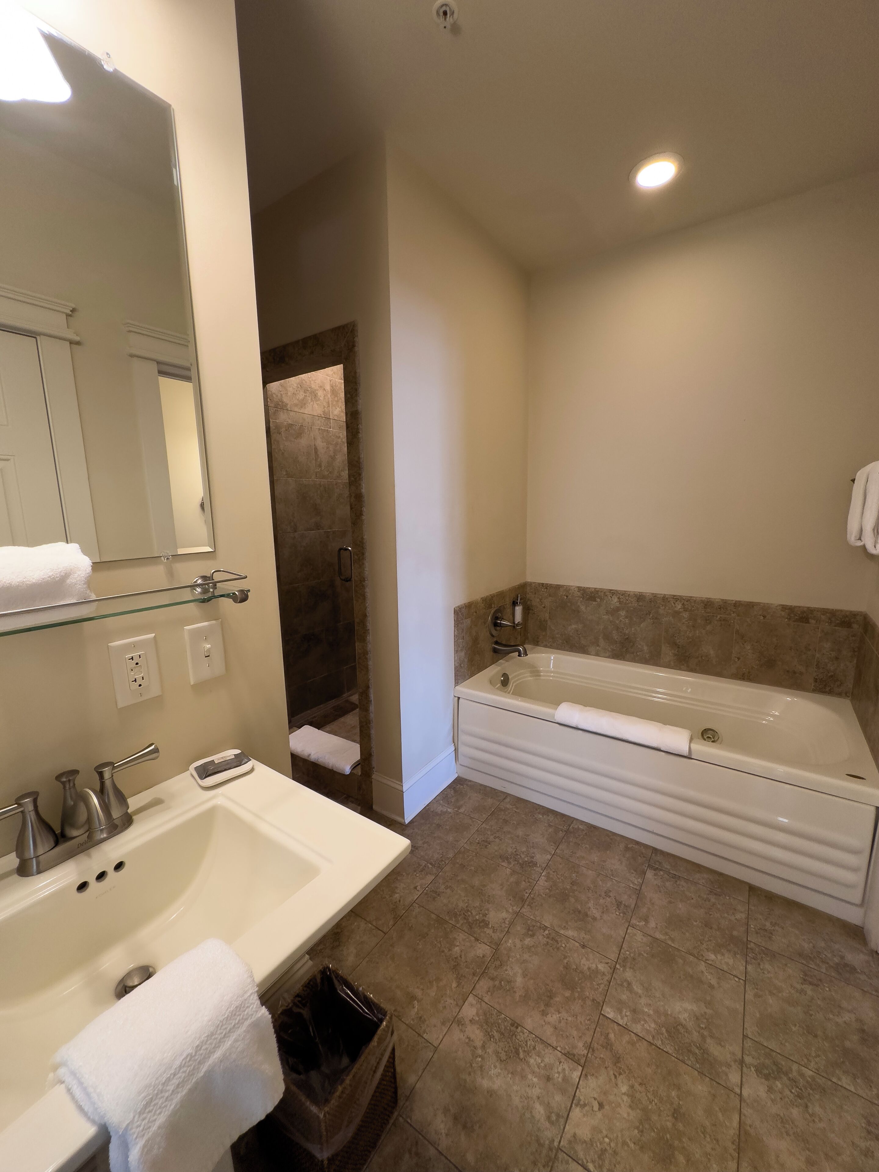 A modern bathroom with a large bathtub, a sink, and a mirror.
