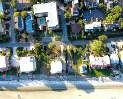 Vista aérea de una zona residencial costera con casas, una playa y una carretera.