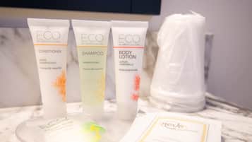 Três embalagens de produtos ECO da Green Culture: condicionador, champô e loção corporal, juntamente com um saco plástico e um cartão sobre uma superfície de mármore.