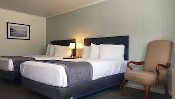 A hotel room with two beds, a chair, and a framed picture on the wall.