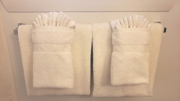 A pair of white towels with pockets hanging on a wall-mounted towel rack.