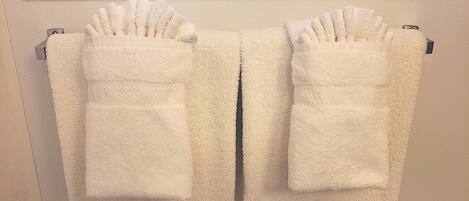 A pair of white towels with pockets hanging on a wall-mounted towel rack.