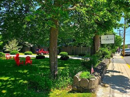 A well-maintained lawn with red Adirondack chairs, a stone wall with an American flag, and a sign for the Anchorage Motel.