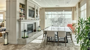 Een moderne eethoek met een grote tafel, stoelen, een open haard en een boekenkast.