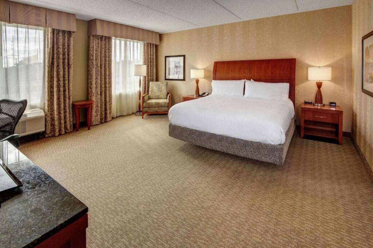 Hotelkamer met een groot bed, een bureau, een stoel, een lamp en een foto aan de muur.