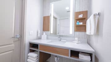 A modern bathroom with a white sink, a large mirror, and wooden shelves.