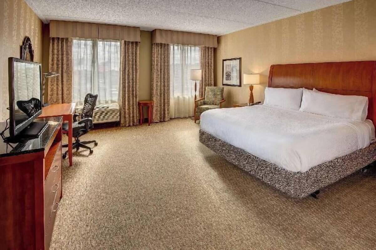 Een hotelkamer met een groot bed, een bureau met een computer, een stoel en een televisie.