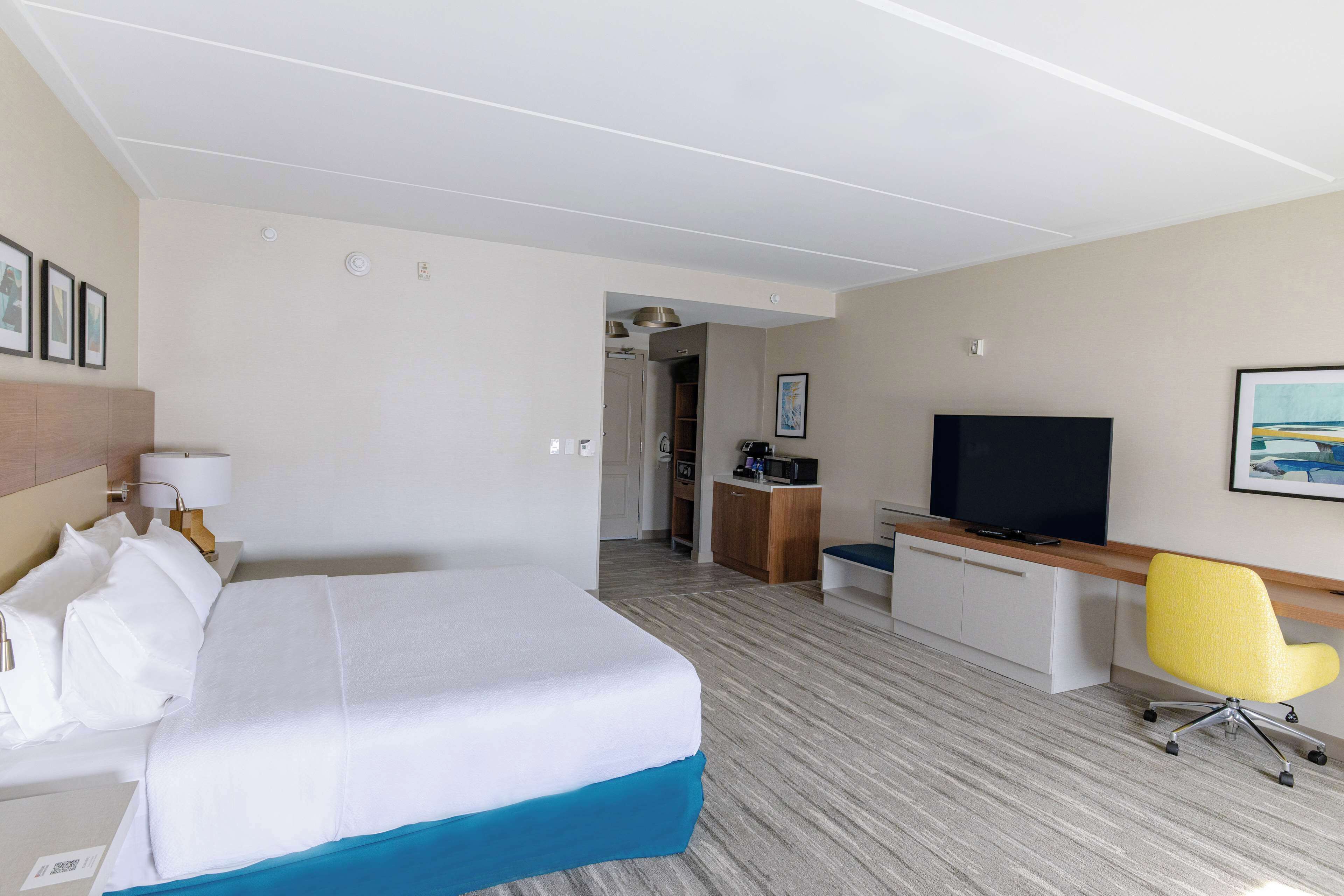 A hotel room with a bed, a desk, a TV, and a chair.