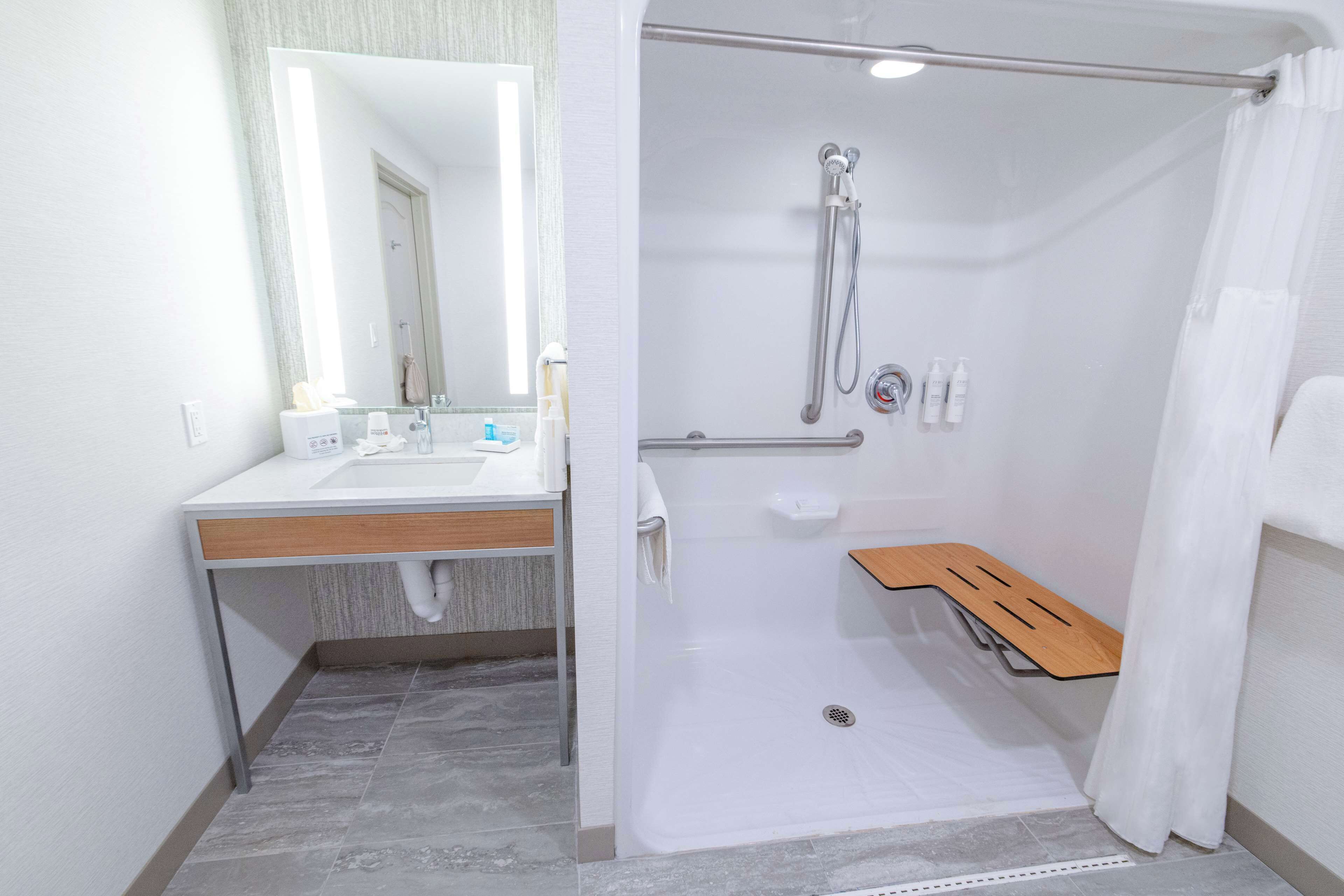 A modern bathroom with a shower, sink, and mirror.