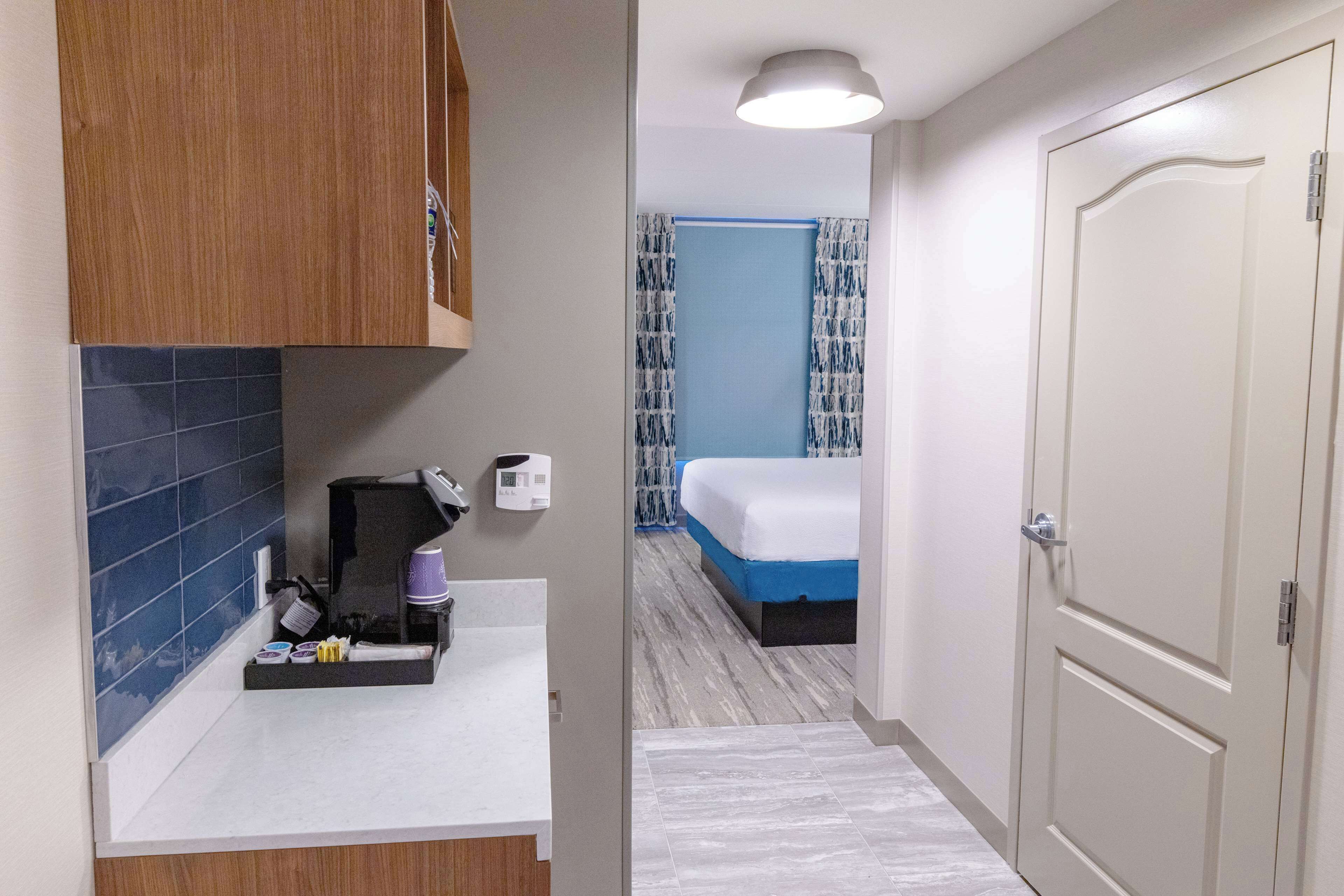 A hotel room with a bathroom, a bed, and a door.