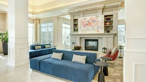 Een ruime woonkamer met een blauwe bank, een open haard en een groot abstract schilderij erboven.