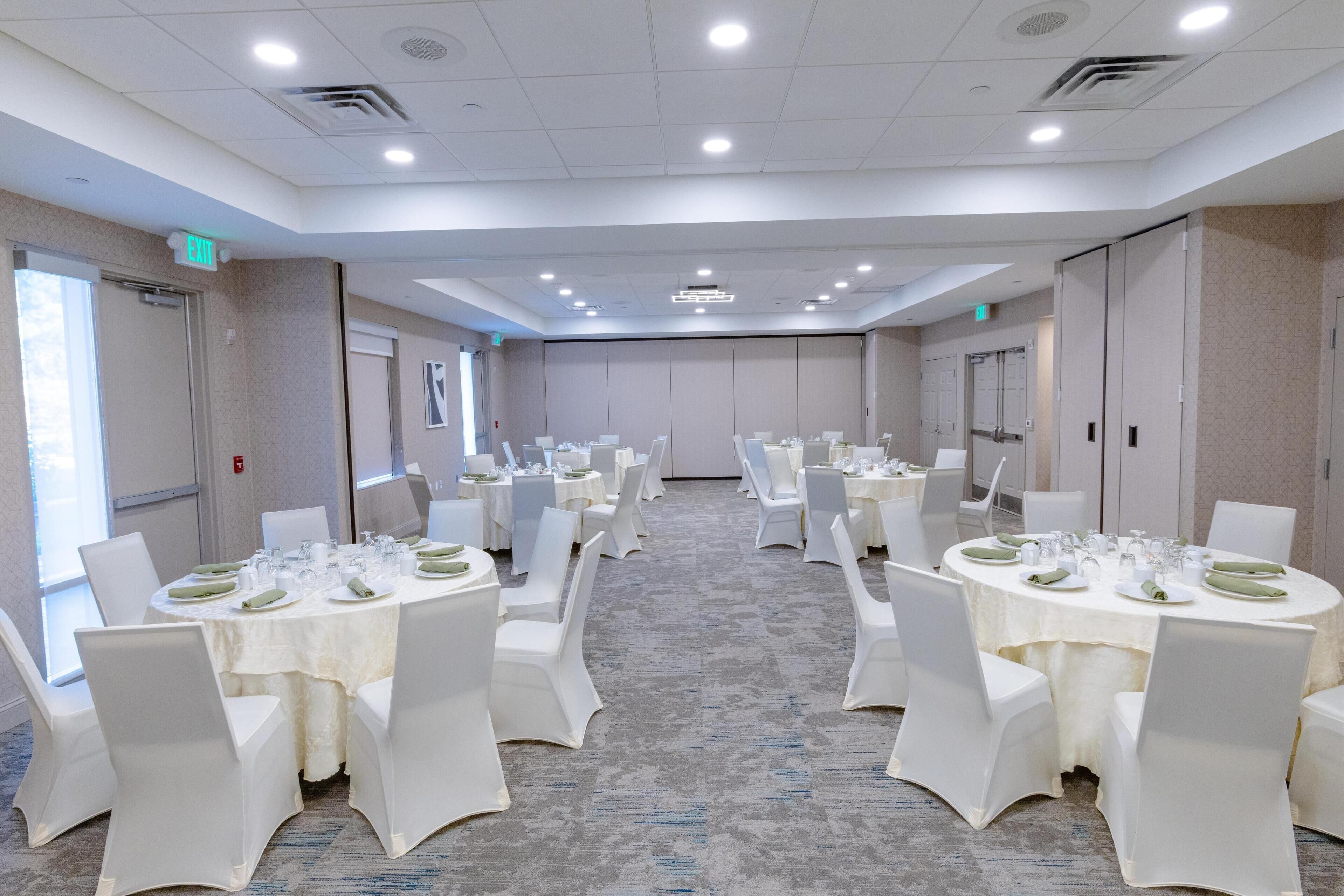 A conference room with multiple tables set for dining, equipped with chairs and table settings.