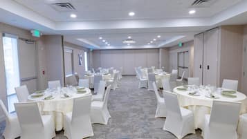 A conference room with multiple tables set for dining, equipped with chairs and table settings.