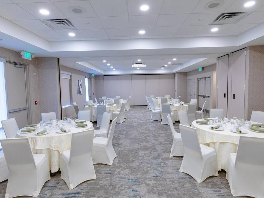 A conference room with multiple tables set for dining, equipped with chairs and table settings.