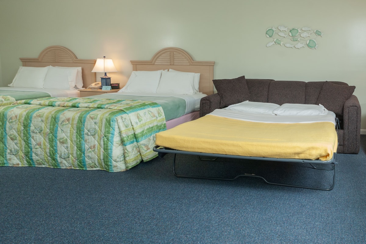 A hotel room with two beds, a nightstand with a lamp, and a wall decoration.