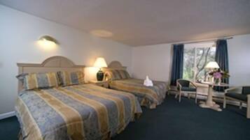 Quarto de hotel com duas camas, uma escrivaninha e uma cadeira.