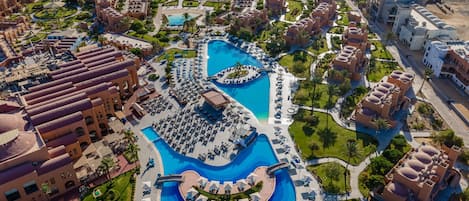 An aerial view of a resort with multiple swimming pools, beach areas, and resort buildings.