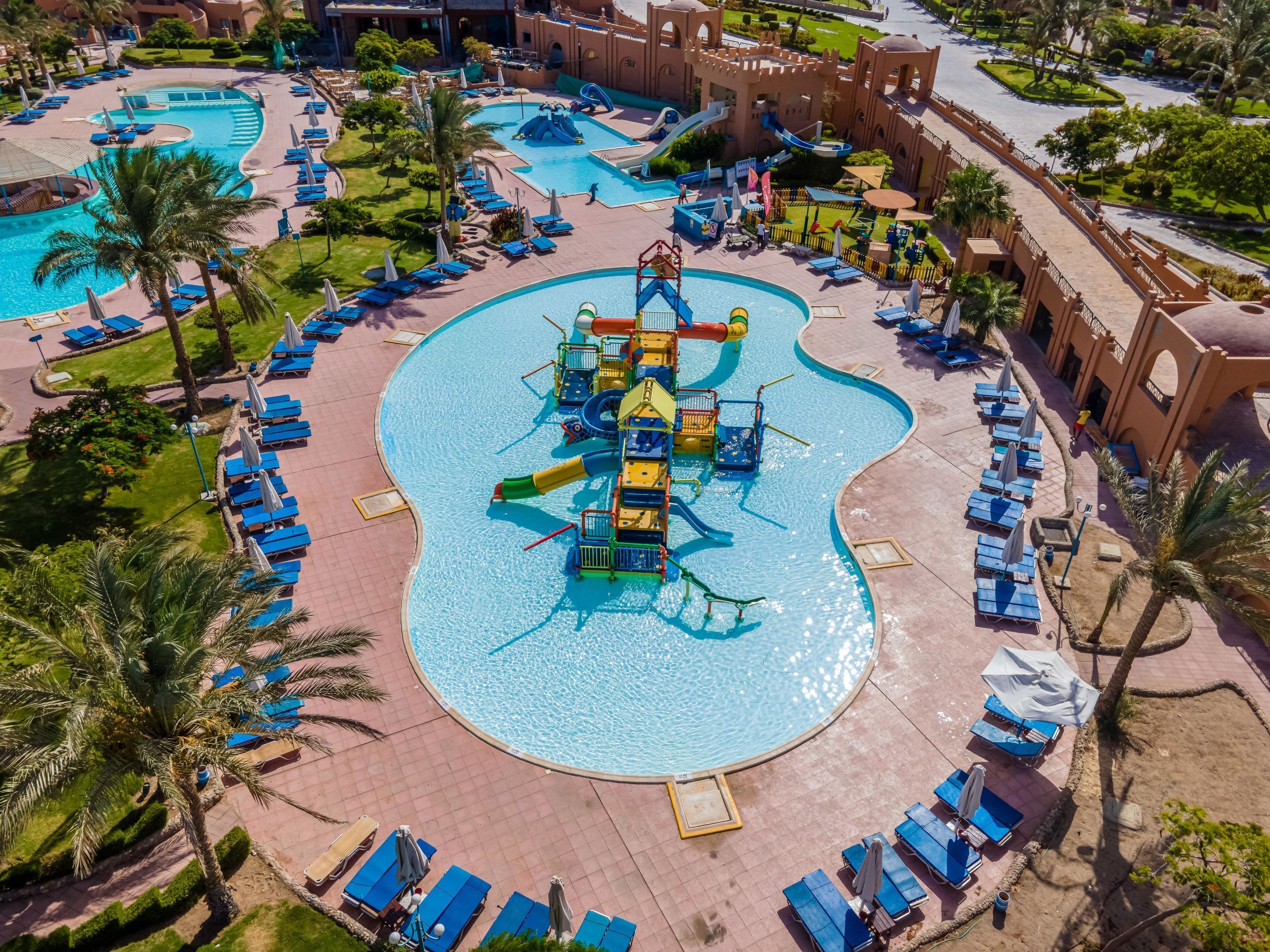 Un complexe hôtelier doté de plusieurs piscines, de toboggans aquatiques et de chaises longues.