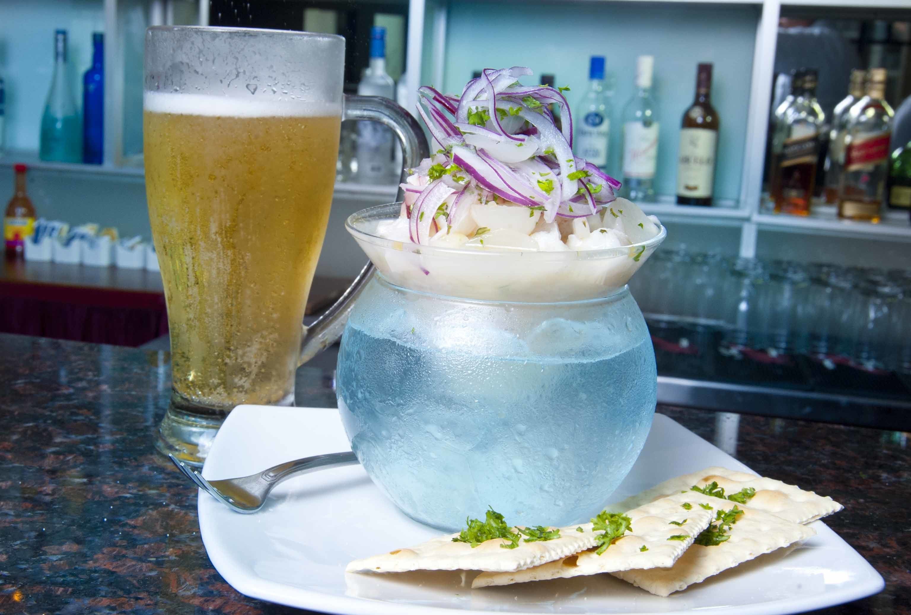 Una cerveza en un vaso y un plato de comida sobre una mesa.