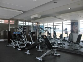A gym with various exercise equipment, large windows, and a view of the outside.