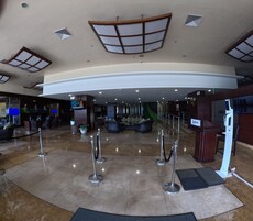 A lobby with a curved ceiling, a reception desk, seating area, and a TV screen.