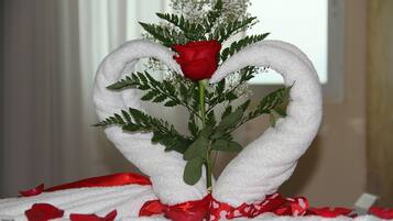 A decorative arrangement with a red rose and white towels shaped like swans.