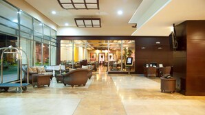 A spacious lobby with a reception desk, comfortable seating, and a glass wall offering a view of the street. - Radisson Colon 2000 Hotel & Casino at Cruise Port & Duty Free Mall (Colon)