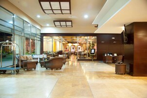 A spacious lobby with a reception desk, comfortable seating, and a glass wall offering a view of the street.